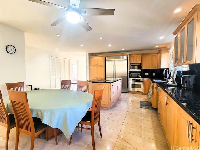 kitchen featuring sink, backsplash, a kitchen island, built in appliances, and light tile patterned flooring