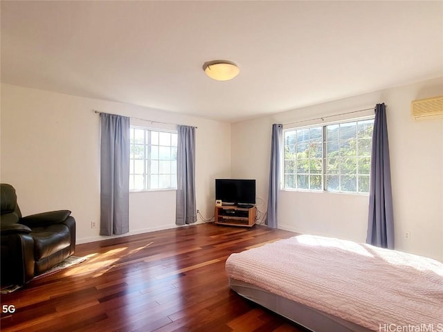 bedroom featuring dark wood-type flooring and an AC wall unit