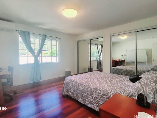 bedroom featuring dark hardwood / wood-style floors, a wall unit AC, and two closets