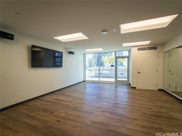 empty room featuring a wall of windows and hardwood / wood-style floors