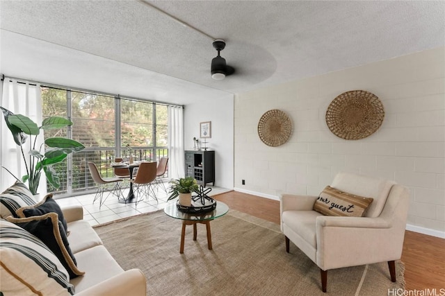 living room with expansive windows, wood-type flooring, ceiling fan, and a textured ceiling