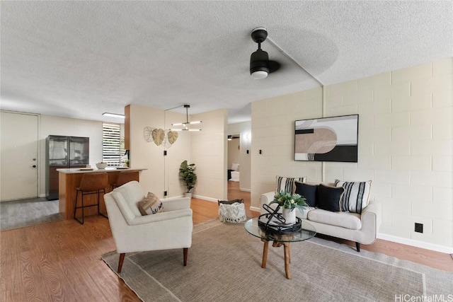 living room with hardwood / wood-style floors, a textured ceiling, and ceiling fan