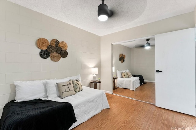 bedroom with a closet, wood-type flooring, and a textured ceiling