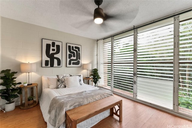 bedroom featuring wood-type flooring, access to outside, ceiling fan, and a textured ceiling