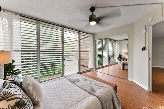 bedroom featuring wood-type flooring, access to exterior, ceiling fan, floor to ceiling windows, and a textured ceiling