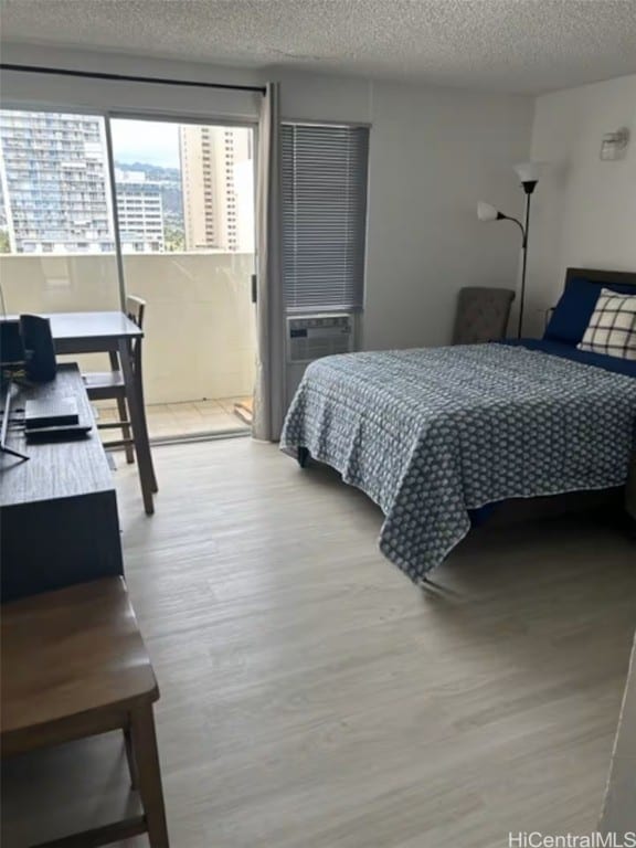 bedroom featuring hardwood / wood-style floors, a textured ceiling, and cooling unit