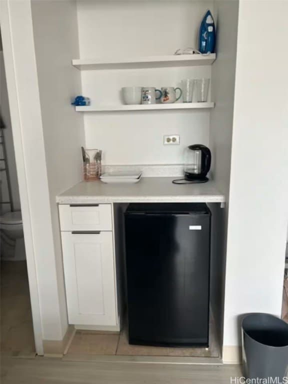 bar featuring fridge and white cabinetry