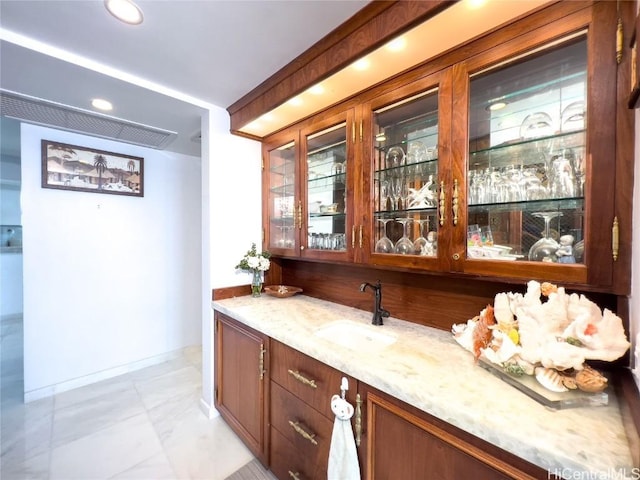 bar featuring light stone countertops and sink