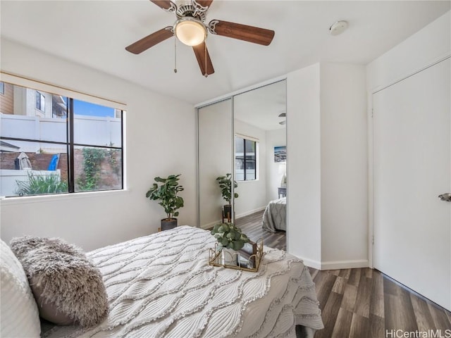 bedroom with dark wood-type flooring, ceiling fan, and a closet