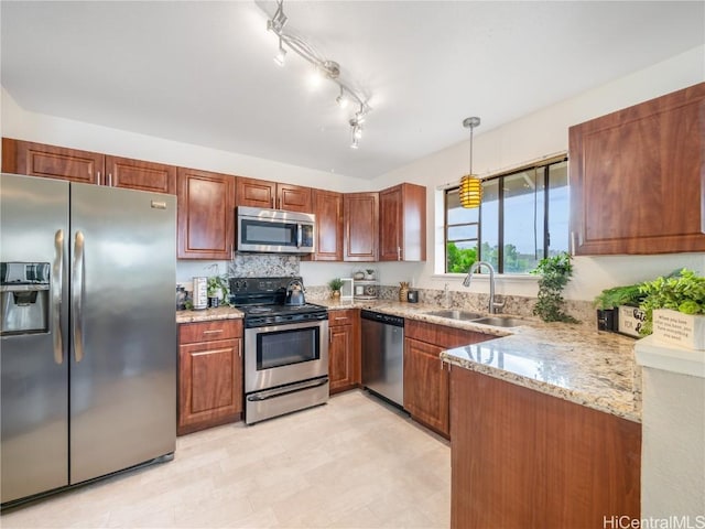 kitchen featuring sink, kitchen peninsula, pendant lighting, stainless steel appliances, and light stone countertops