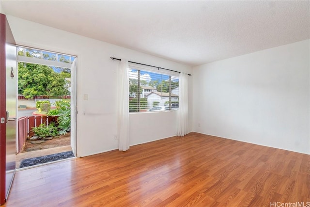 unfurnished room featuring light hardwood / wood-style flooring and a textured ceiling