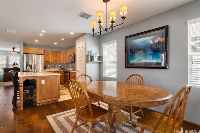 dining area featuring dark hardwood / wood-style flooring, sink, and ceiling fan with notable chandelier