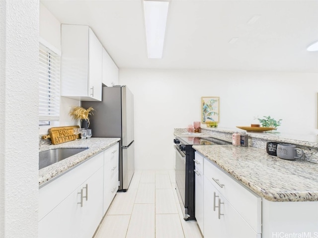 kitchen featuring light stone counters, light tile patterned floors, a sink, black electric range, and white cabinets