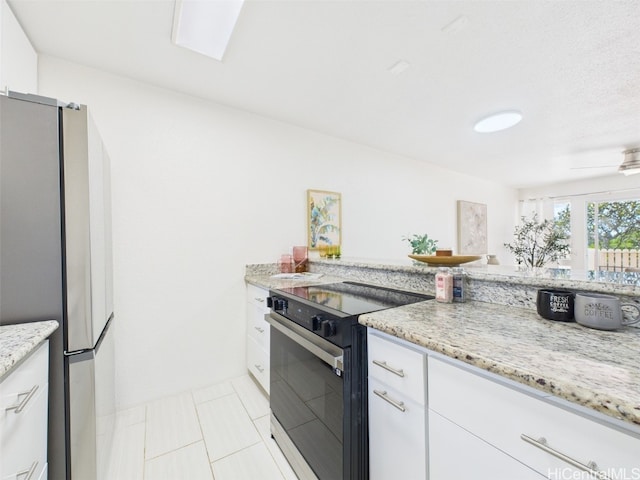 kitchen with white cabinets, light stone countertops, freestanding refrigerator, and black electric range