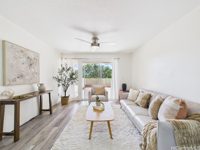 living area with baseboards, a textured ceiling, wood finished floors, and a ceiling fan