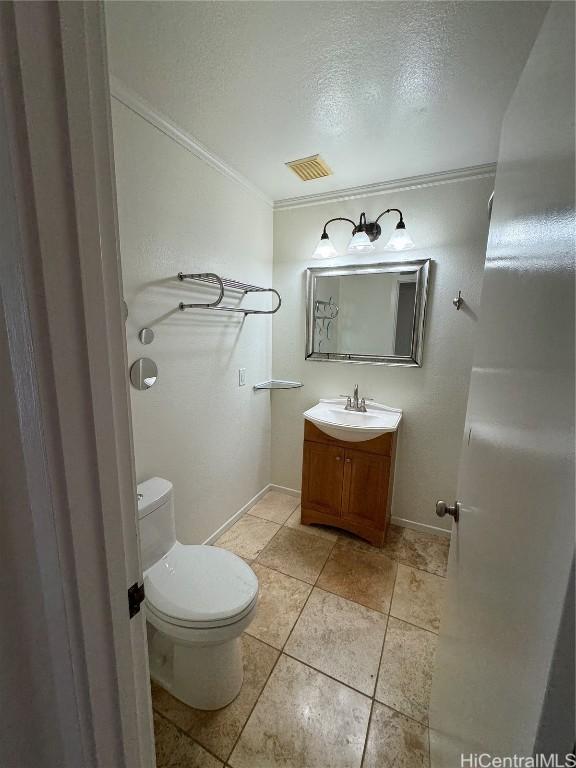 bathroom featuring vanity, ornamental molding, a textured ceiling, and toilet