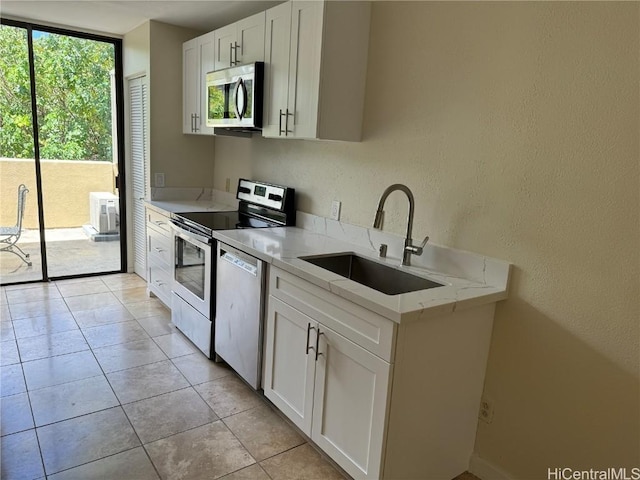 kitchen featuring light stone counters, sink, white cabinets, and appliances with stainless steel finishes