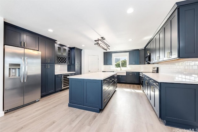 kitchen with backsplash, beverage cooler, a center island, and appliances with stainless steel finishes