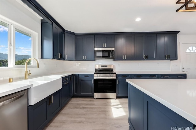 kitchen with sink, decorative backsplash, light hardwood / wood-style flooring, and appliances with stainless steel finishes