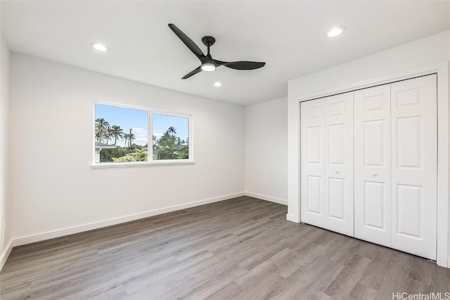 unfurnished bedroom featuring ceiling fan, a closet, and light wood-type flooring