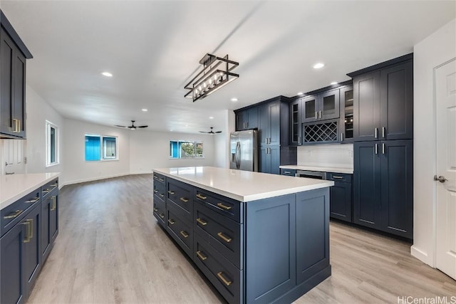 kitchen with ceiling fan, stainless steel fridge, a center island, and light wood-type flooring