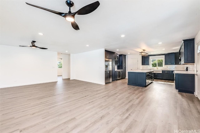 unfurnished living room with sink, light hardwood / wood-style flooring, and ceiling fan