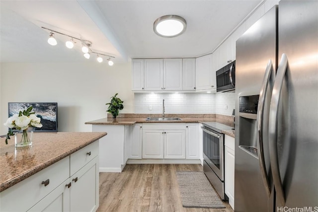 kitchen with sink, appliances with stainless steel finishes, white cabinetry, stone countertops, and light wood-type flooring