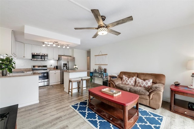 living room with ceiling fan and light wood-type flooring