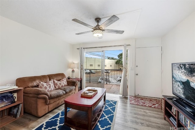 living room featuring hardwood / wood-style flooring, ceiling fan, and a textured ceiling