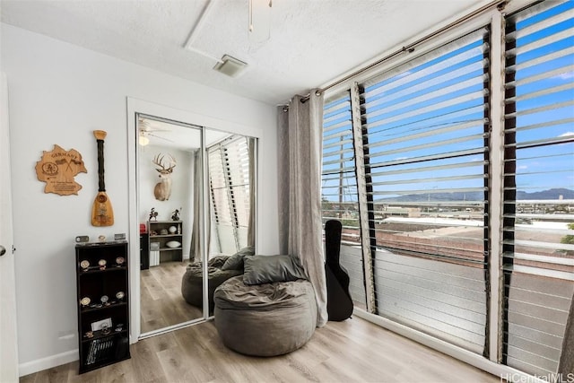 sitting room with wood-type flooring, a mountain view, ceiling fan, and a textured ceiling