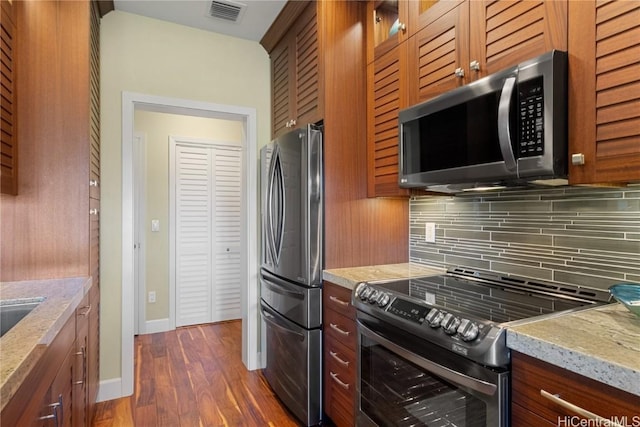 kitchen with tasteful backsplash, dark hardwood / wood-style flooring, light stone countertops, and appliances with stainless steel finishes