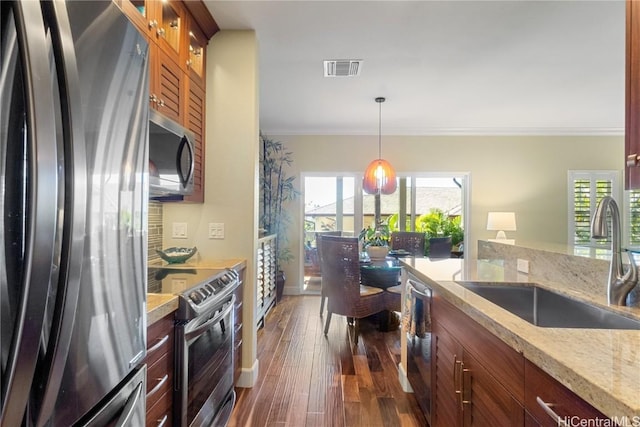 kitchen with sink, light stone counters, appliances with stainless steel finishes, dark hardwood / wood-style flooring, and pendant lighting