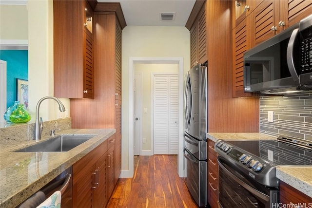 kitchen featuring sink, tasteful backsplash, dark hardwood / wood-style floors, stainless steel appliances, and light stone countertops