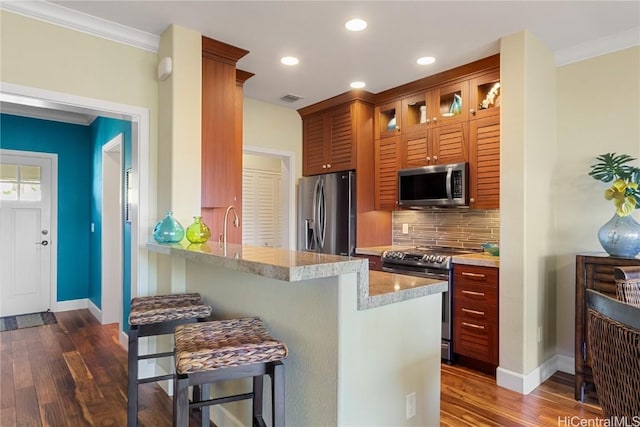 kitchen featuring tasteful backsplash, stainless steel appliances, dark wood-type flooring, and a breakfast bar area