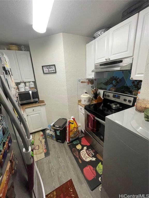 kitchen featuring light hardwood / wood-style flooring, appliances with stainless steel finishes, backsplash, a textured ceiling, and white cabinets