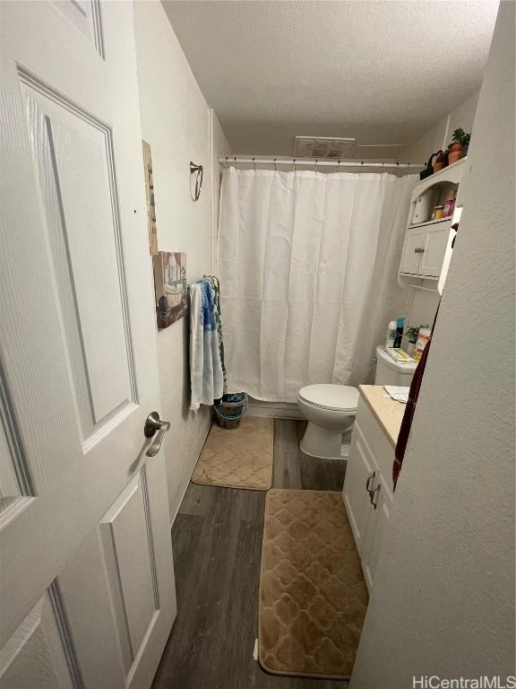 bathroom featuring vanity, hardwood / wood-style flooring, a textured ceiling, and toilet