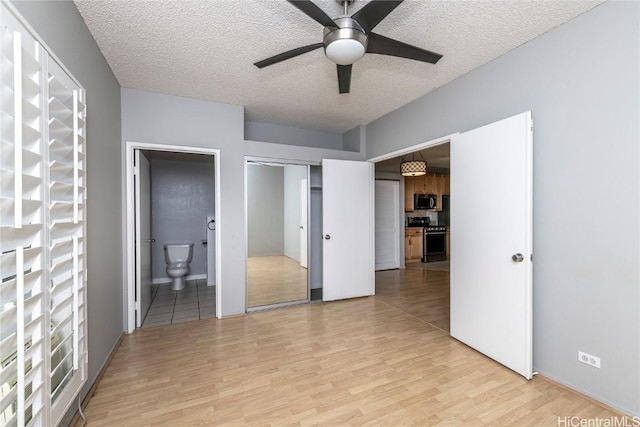 unfurnished bedroom featuring light hardwood / wood-style floors, a closet, a textured ceiling, and ensuite bathroom