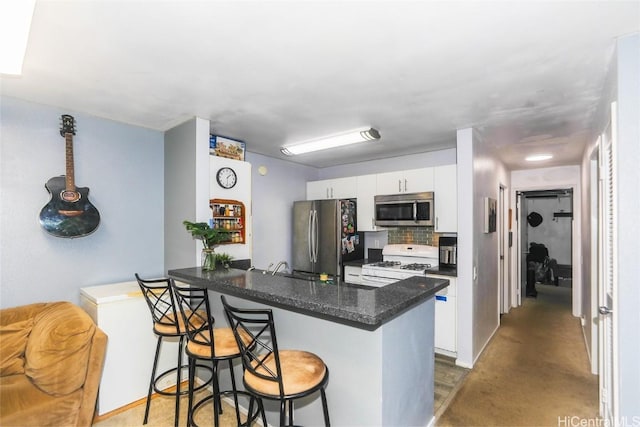 kitchen featuring white cabinetry, a breakfast bar area, kitchen peninsula, and appliances with stainless steel finishes