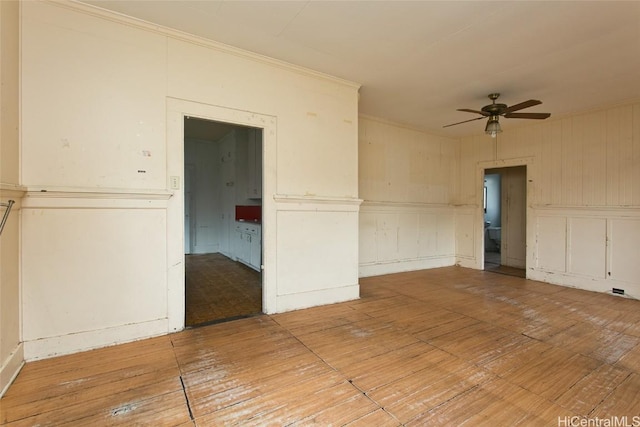 empty room featuring hardwood / wood-style flooring, crown molding, and ceiling fan