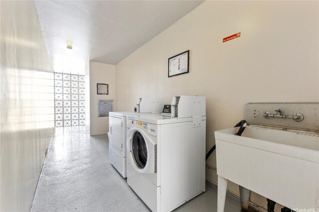 laundry area with separate washer and dryer and a sink