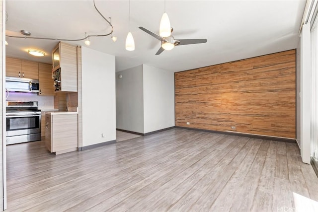 unfurnished living room with hardwood / wood-style flooring, ceiling fan, and wood walls