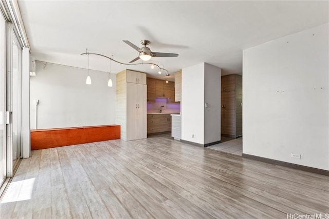 unfurnished living room with sink, ceiling fan, and light hardwood / wood-style floors