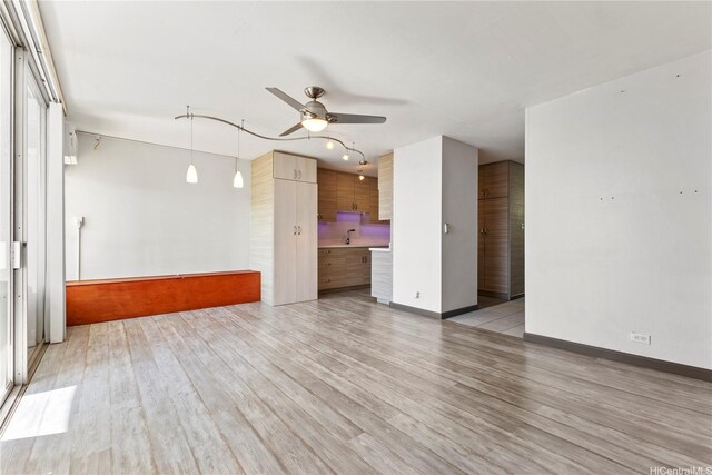 spare room with ceiling fan, light wood-style flooring, a sink, and baseboards
