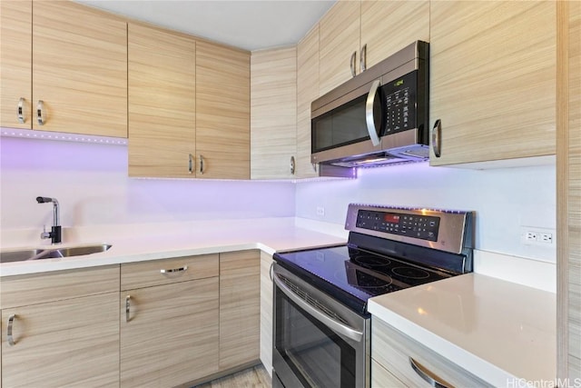 kitchen with stainless steel appliances, light brown cabinetry, and sink