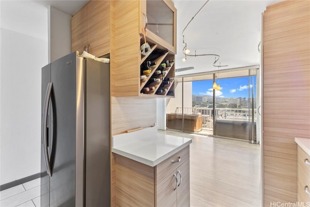 kitchen featuring stainless steel refrigerator, hanging light fixtures, and a wall of windows