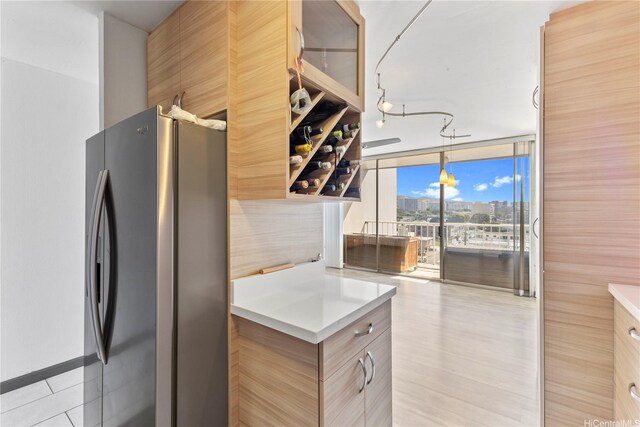 kitchen featuring freestanding refrigerator, a wall of windows, light countertops, and modern cabinets