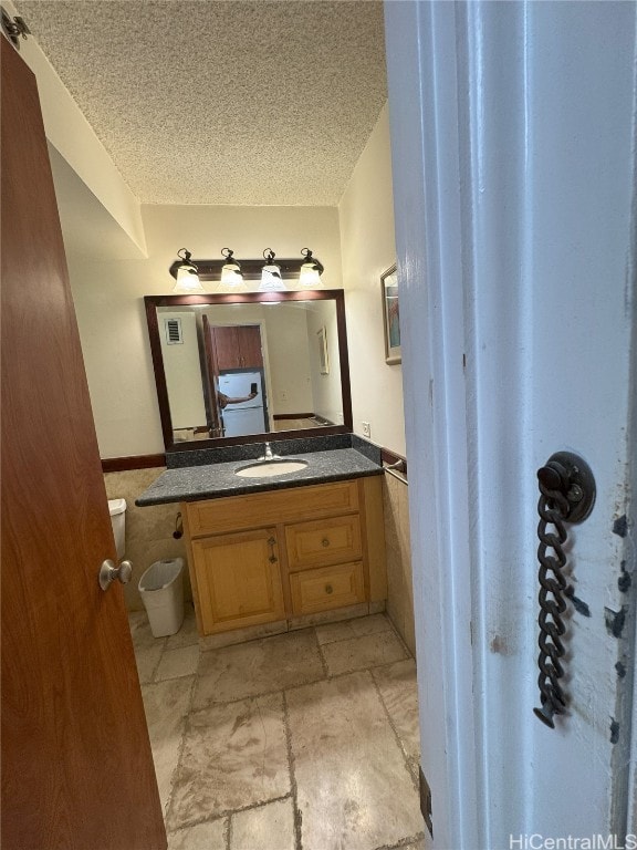 half bathroom featuring a textured ceiling and vanity