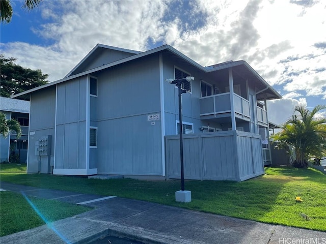 view of side of property featuring a balcony and a yard