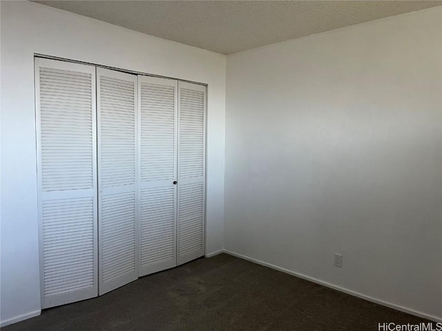 unfurnished bedroom featuring a closet and dark colored carpet