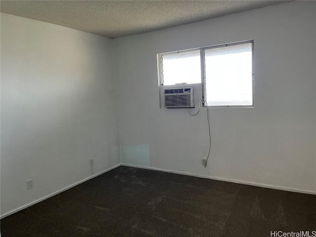 empty room with cooling unit, dark carpet, and a textured ceiling